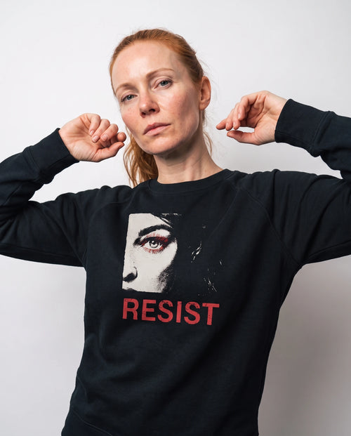gravisk Resist v1 graphic sweatshirt in organic cotton. Half a face with one open eye, red lashes and the word resist in worn red.