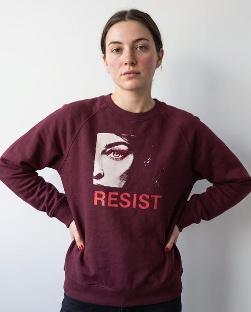 gravisk Resist v1 graphic sweatshirt in organic cotton. Half a face with one open eye, red lashes and the word resist in worn red.