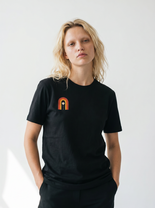 gravisk Bloom Arch organic graphic tee. Left-chest arch in amber and burnt orange, a single flower growing inside.