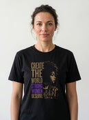 gravisk Create The World Strong Women Deserve organic graphic tee. A woman's profile beside a city skyline, gold type with STRONG WOMEN in purple.