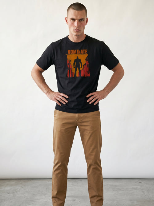 gravisk Dominate organic graphic tee. A lone silhouette in a burning amber street, DOMINATE in heavy caps above.