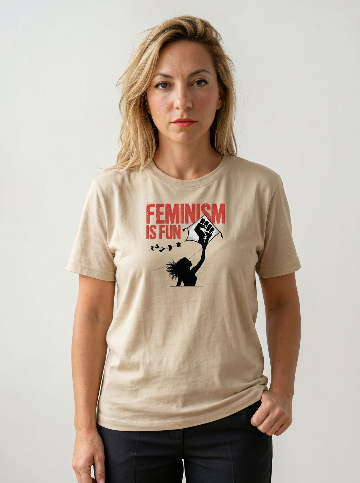 gravisk Feminism Is Fun organic graphic tee. A leaping woman flying a raised-fist kite, red FEMINISM IS FUN type.