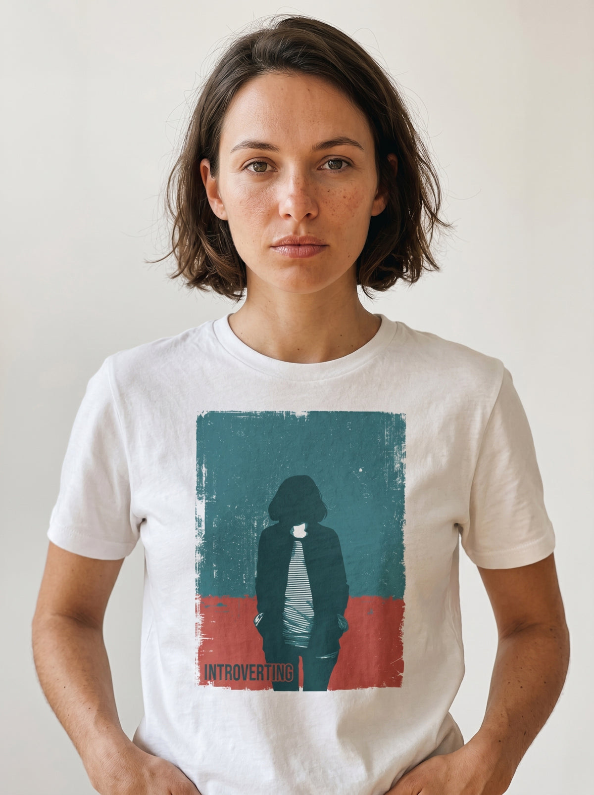 gravisk Introverting organic graphic tee. Worn teal and red poster of a faceless figure, hands in pockets, small INTROVERTING type.