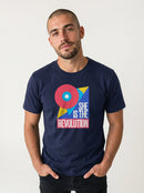 gravisk She Is the Revolution organic graphic tee. Bold geometric shapes in pink, blue and yellow around SHE IS THE REVOLUTION.