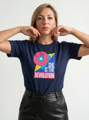 gravisk She Is the Revolution organic graphic tee. Bold geometric shapes in pink, blue and yellow around SHE IS THE REVOLUTION.