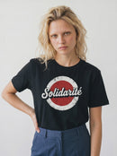 Person wearing a black t-shirt with 'Solidarité' graphic design on a plain background